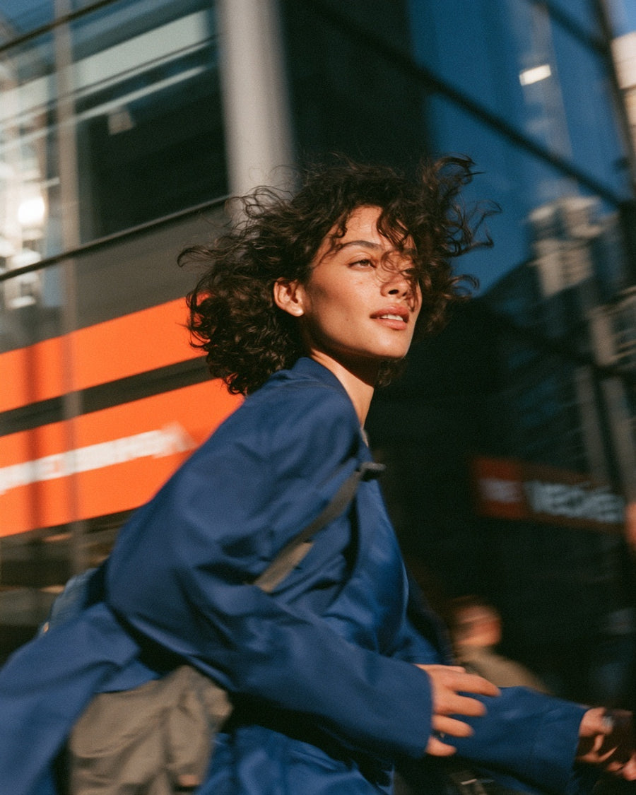 Person in a blue jacket moving through a city street.